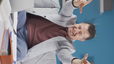 vertical video of home office worker old man makes heart symbol looking at camera.