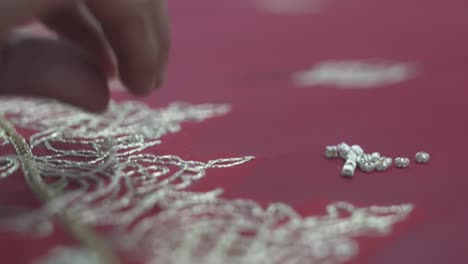 beads being stitched by hand with cotton thread onto beautiful sari wedding dress