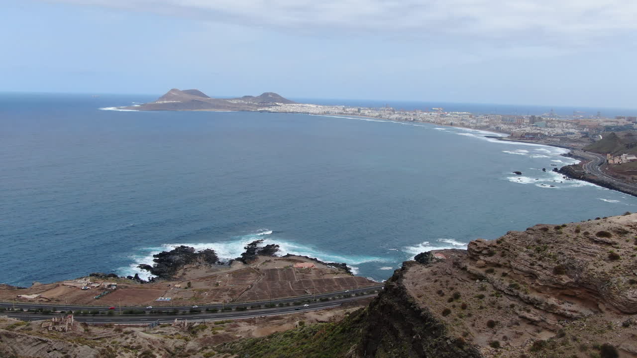 maravillosa toma aerea en lo alto de una montaña y donde se puede ver una vista panoramica de la ciudad de las palmas y la playa de las canteras