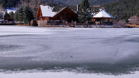 primera nieve hielo congelado cubierto blanco siempre verde lago casa montaña rocosa paisaje escena mañana frente rango denver aéreo cinematográfico dron navidad patinaje sobre hielo hockey cielo azul pan hacia adelante movimiento