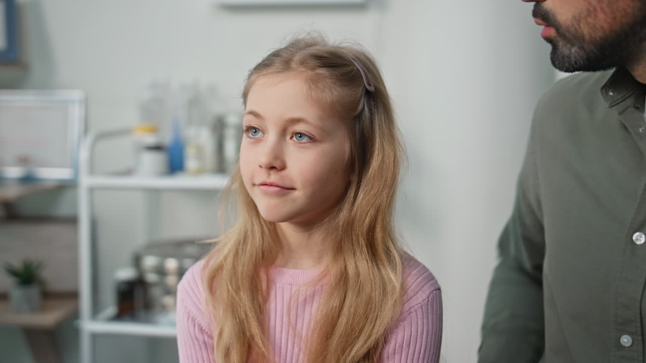 Child complaining sore throat in clinic closeup. Cute girl talk unknown doctor