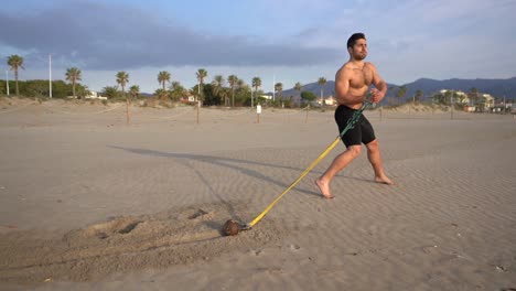 hacer ejercicio en la playa con zancada larga ofreciendo resistencia con peso