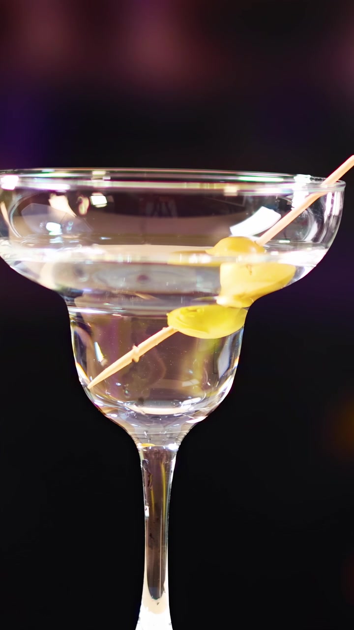 Mano che posiziona una guarnizione di oliva in un bicchiere da Martini