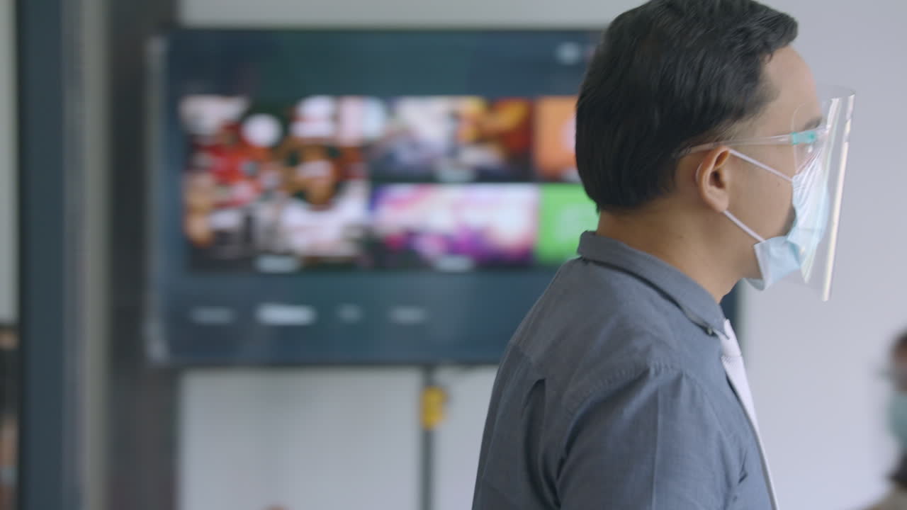 코로나 바이러스로 인해 안면 마스크와 안면 보호대를 착용하고 회의실로 걸어가는 사업가