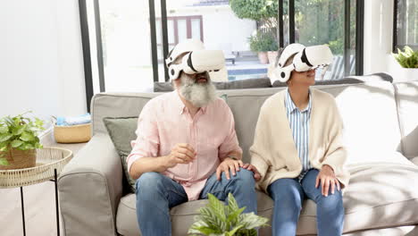 using vr headsets, senior couple sitting on sofa and interacting with virtual world