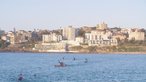 Wasserübungskonzept---Kajakfahrer-Und-Schwimmer-Draußen-Am-Strand-Von-North-Bondi-In-Australien