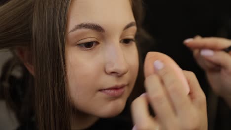 detailed close-up of makeup application using a beauty blender to achieve a flawless look