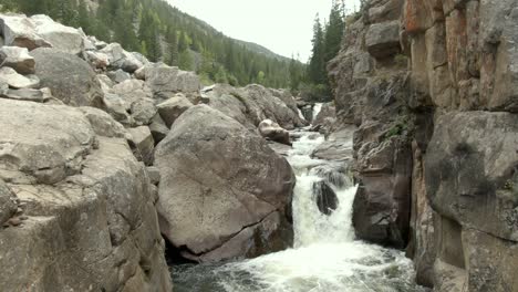 aerial rising out of canyon with waterfall and river in colorado