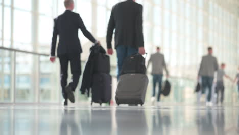 woman in business outfit walking in slow motion, man with suitcases in the background