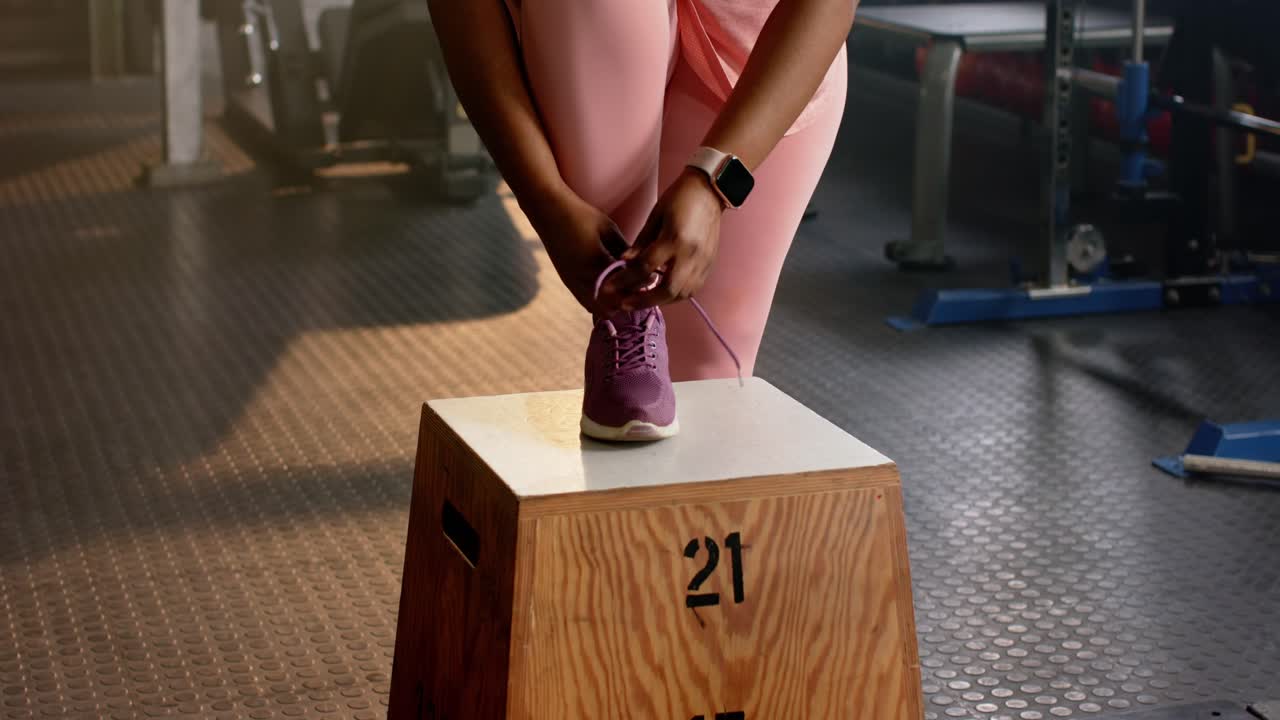 Donna che entra in palestra e appoggia il piede sulla casella numero 21, poi si allaccia strettamente le scarpe per allenarsi