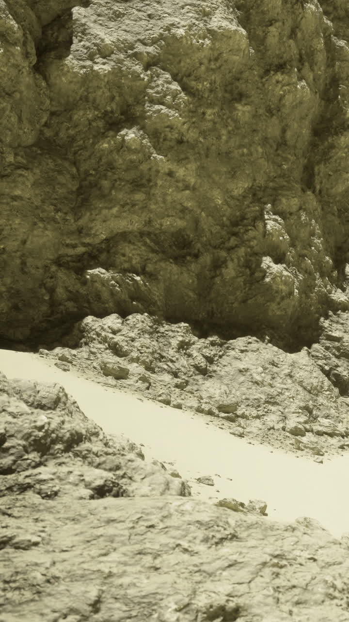 Rocky landscape with sandy area in the foreground and textured rock formation