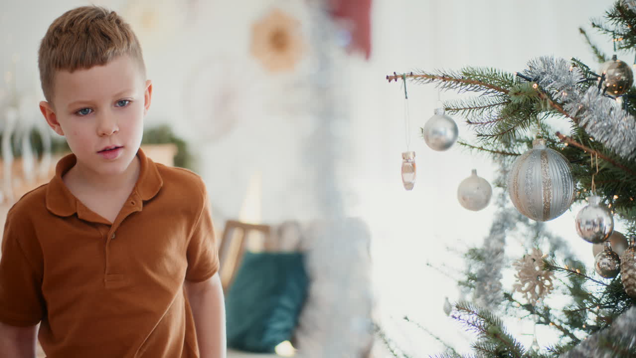 어린 소년은 크리스마스 트리를 은색 크리스마스 나무 사슬로 장식합니다.