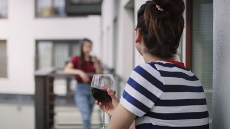 handheld video of neighbors drinking wine on the balcony