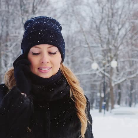 una mujer camina en un parque de invierno usa un teléfono inteligente