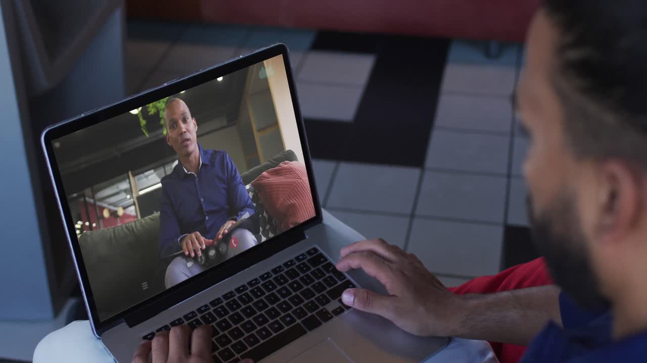 Middle eastern man having a video call with male office colleague on laptop