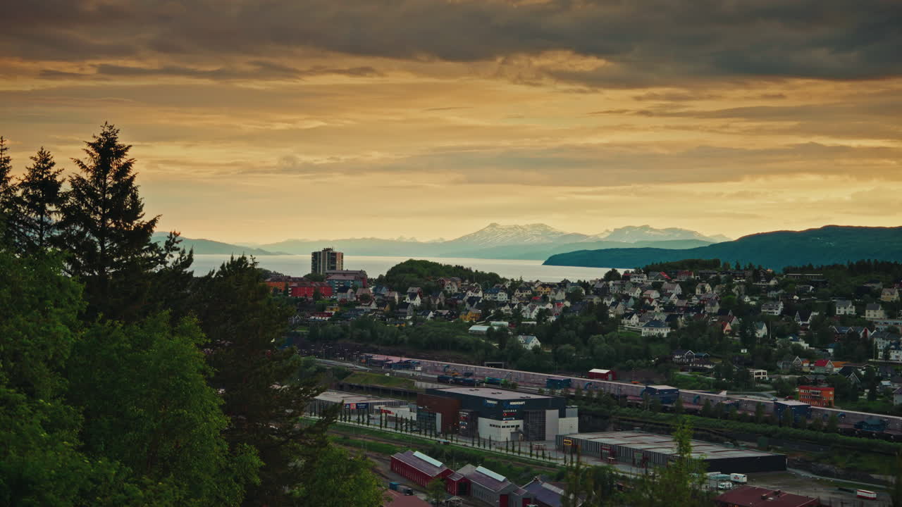 Midnight sunset over the nordic city of Narvik in Norway. View of the majestic fjords, the Norwegian sea and the cloudy, golden sky.
Picturesque arctic landscape.