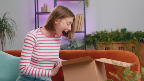 Happy-young-woman-shopper-unpacking-cardboard-box-delivery-parcel-online-shopping-purchase-at-home