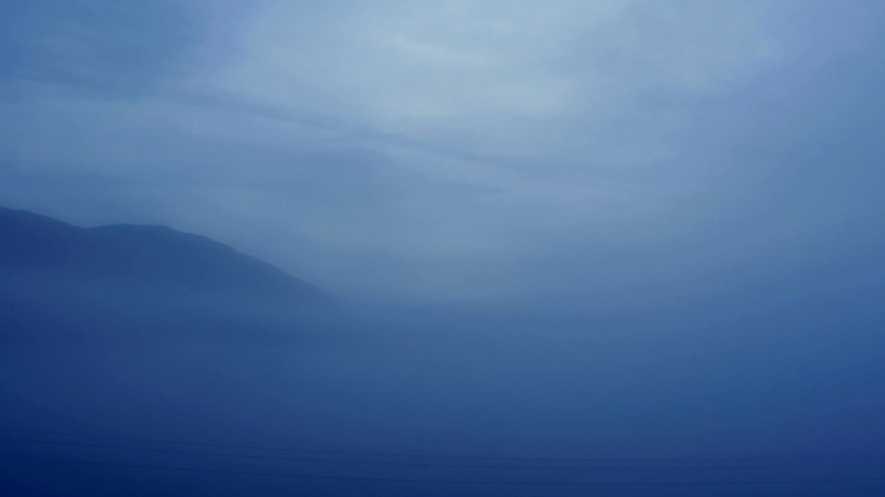 안개가 자욱한 산길 뒤에 태양이 빛난다