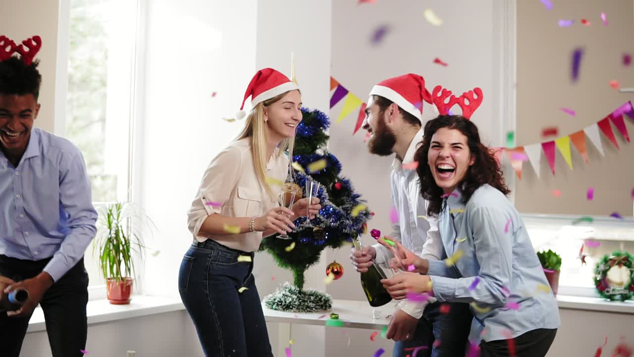 un grupo de jóvenes celebrando navidad y año nuevo en la oficina abriendo una botella de vino espumoso y petardos con