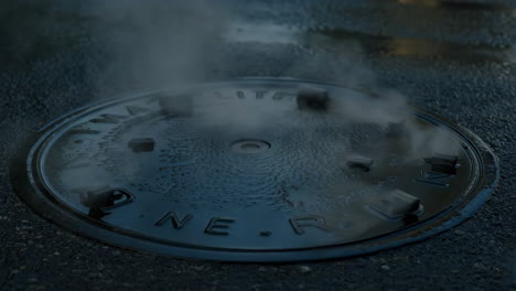 manhole cover with steam on a wet street
