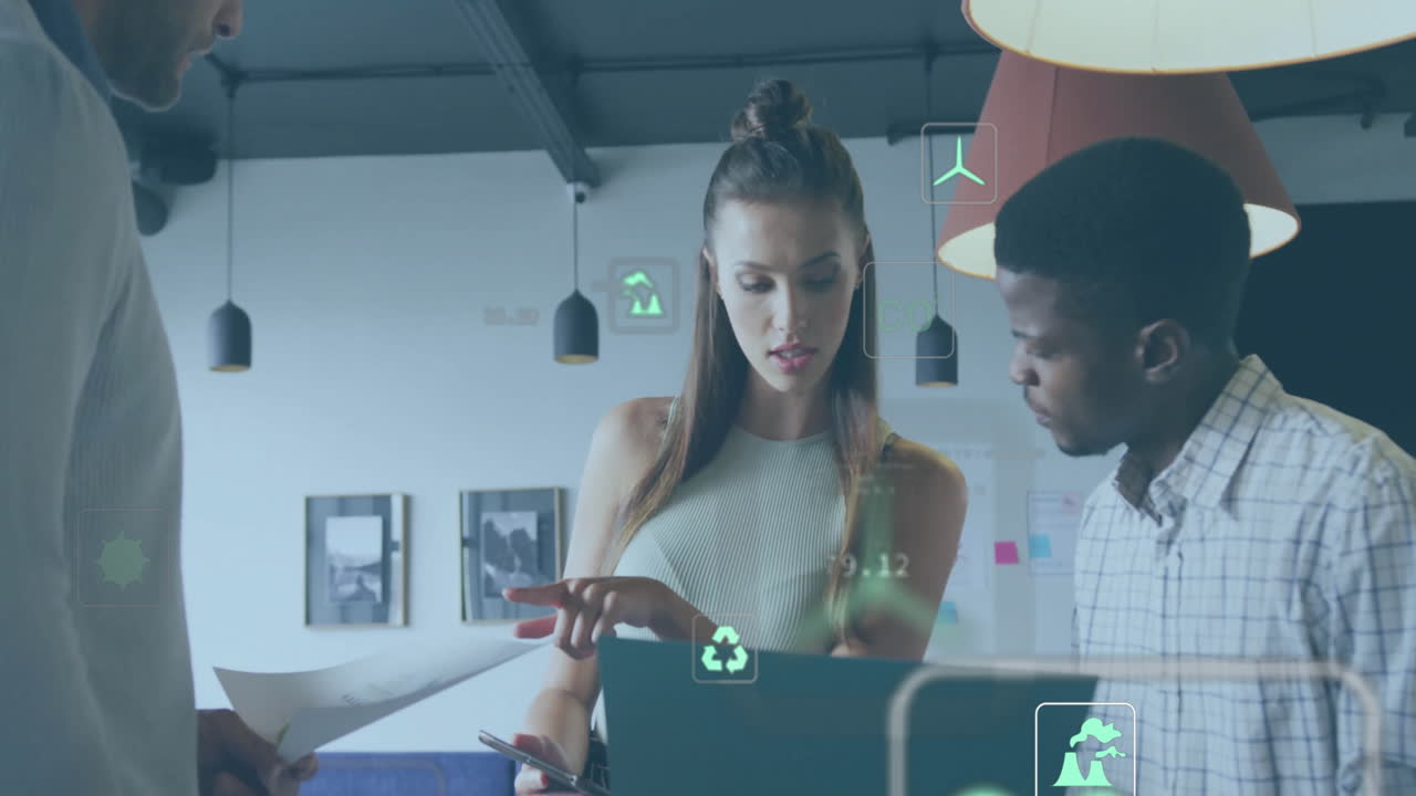 Animation of ecology icons over diverse colleagues using laptop and discussing work in office