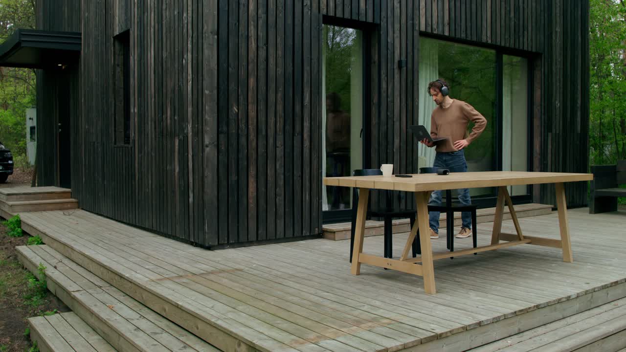 hombre trabajando en una computadora portátil al aire libre en una cubierta de madera