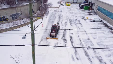 Traktor-Mit-Schneepflug-Reinigt-Privaten-Parkplatz-In-Kanada,-Luftaufnahme