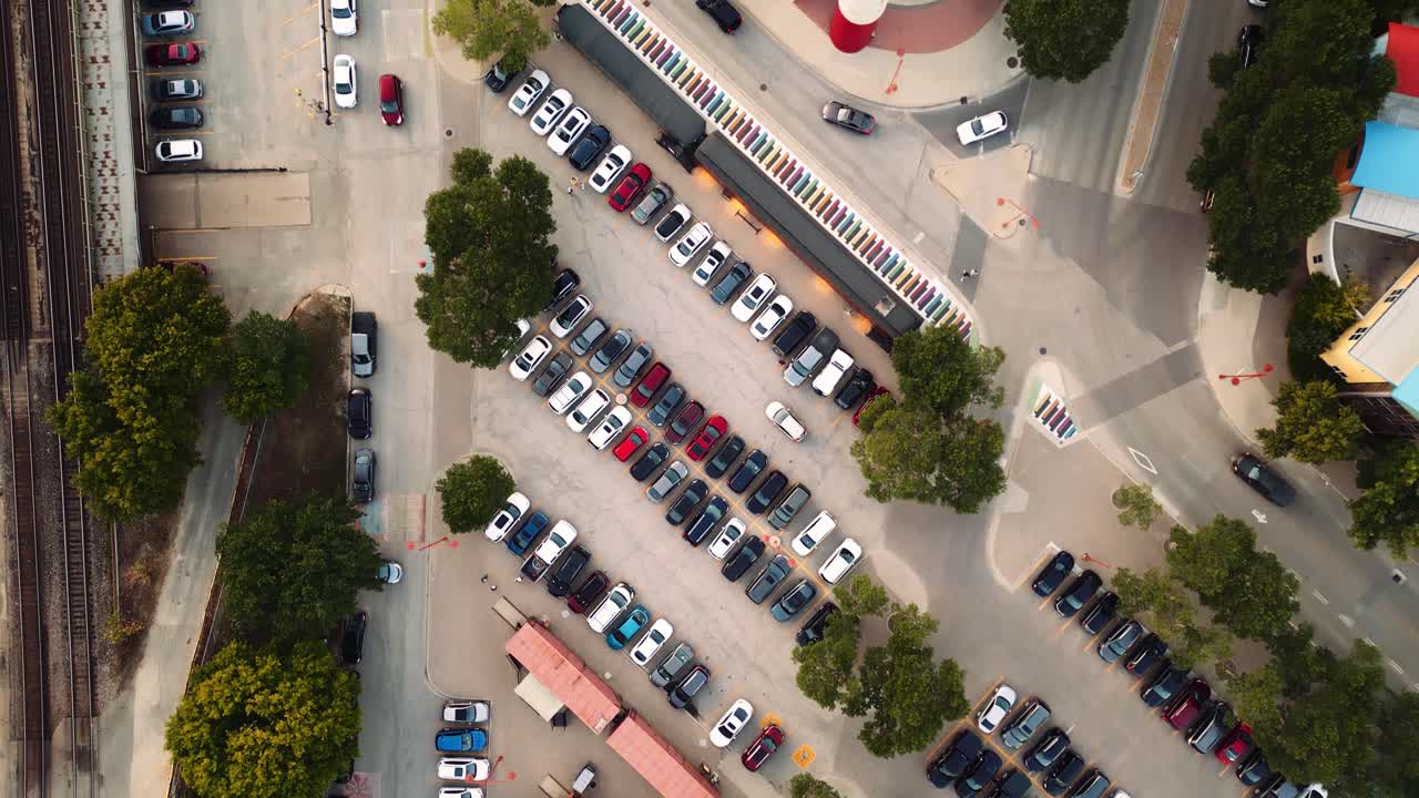 vista aérea de arriba hacia abajo disparo de avión no tripulado cinematográfico de varios estacionamientos de ciudades metropolitanas boscosas llenas de coches multicolores vehículos y personas en el verano