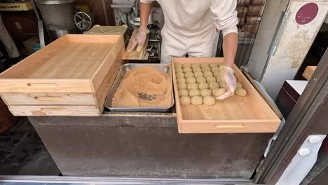 Trabajador-Japonés-Que-Cubre-Mochi-Con-Harina-De-Kinako-En-Una-Confitería-En-Nara,-Japón