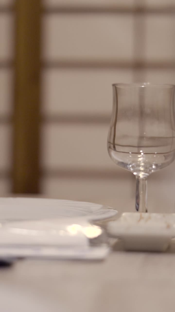 Close-up shots of a table setting with a glass, tableware, and book, featuring bokeh effects