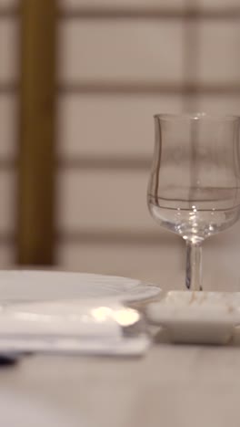 close-up shots of a table setting with a glass, tableware, and book, featuring bokeh effects