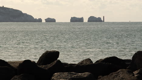 distant-shot-of-the-Isle-of-Wight-needles-with-lighthouse-filmed-with-see-defence-rocks-in-foreground-at-Milford-on-sea