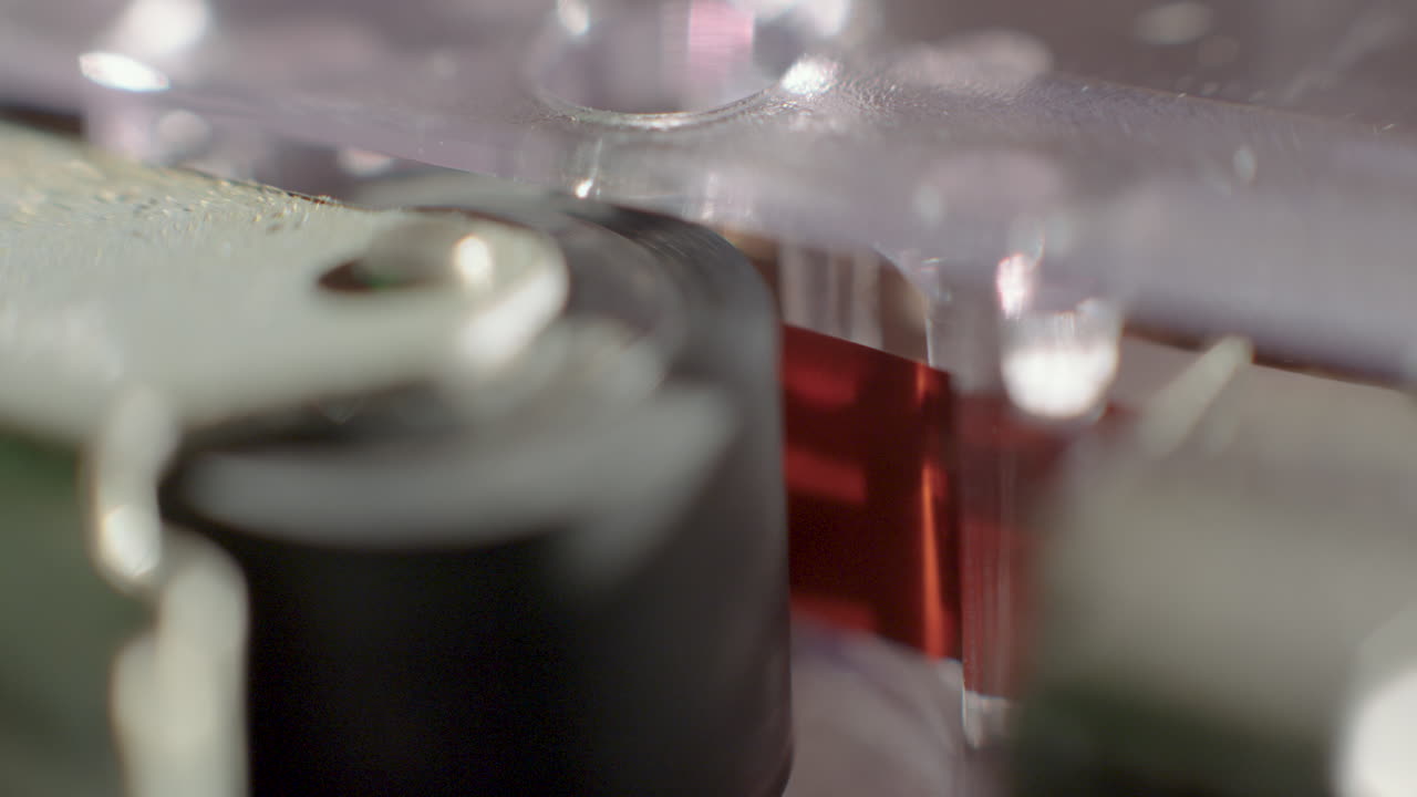 primer plano extremo de la cinta de cinta grabadora de microcassette que se ejecuta bajo el rodillo de arrastre