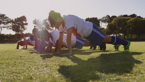 Female-soccer-players-doing-push-ups-on-soccer-field.-4k