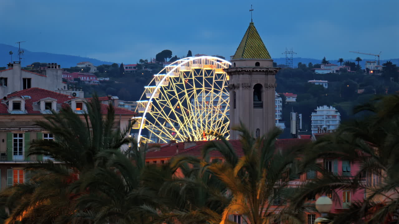 Distant view of a ferris wheel along the Mediterranean coast of the city in the evening in Nice, France