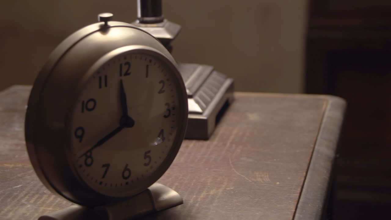 Een oude klok rust op een antieke tafel, zacht verlicht door een warme lamp terwijl de camera soepel van links naar rechts glijdt