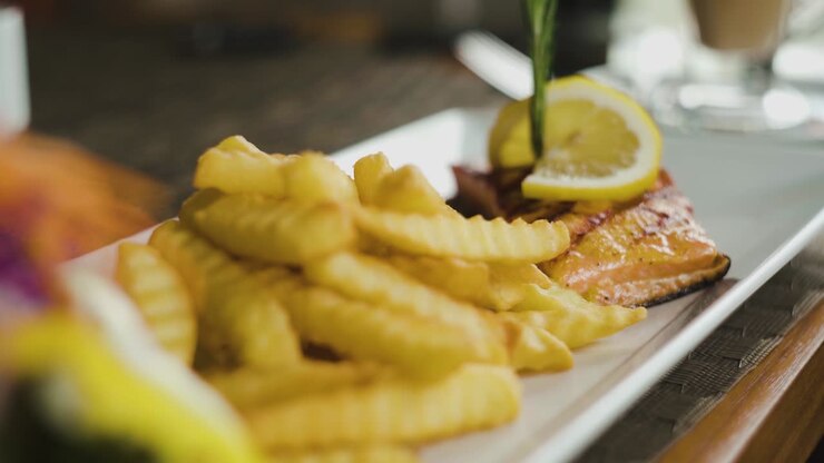 Salmon steak with french fries on side close up static shot with slow zoom out