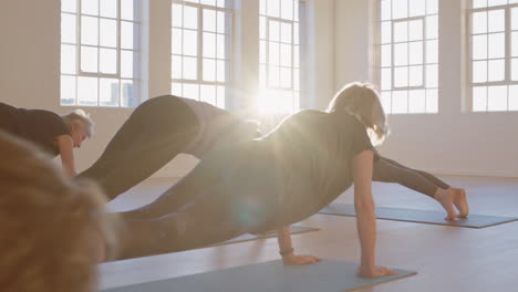 yoga class instructor teaching mature women practicing plank pose enjoying healthy lifestyle in fitness studio at sunrise