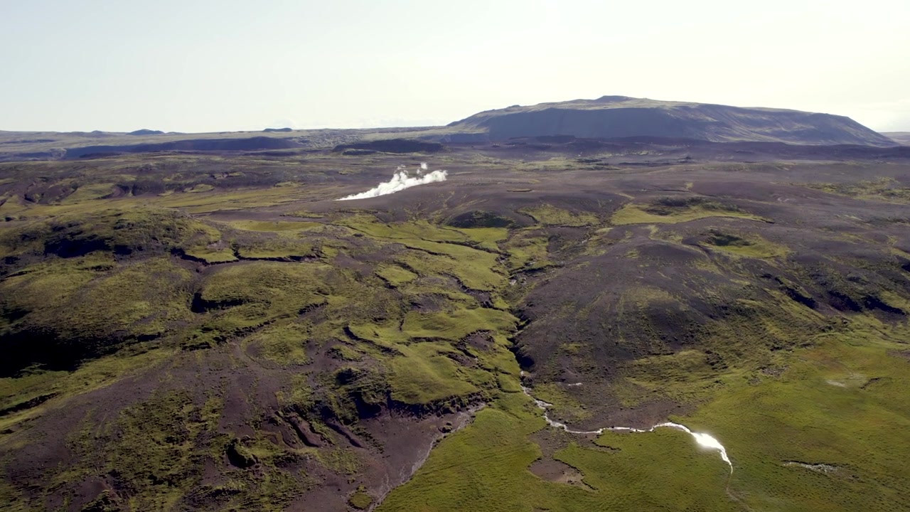 なだらかな丘と自然の地形に囲まれた間欠泉が広がるアイスランドのドローン映像