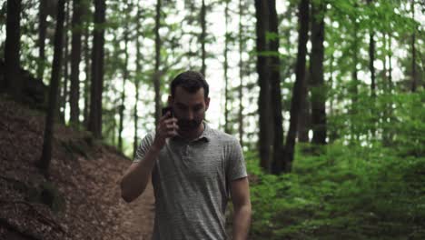 hombre caucásico perdido en el bosque usando un teléfono móvil sin recepción, tratando de encontrar una salida