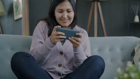 woman playing mobile game on couch