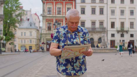 älterer,-Stilvoller-Tourist,-Großvater,-Der-Die-Straße-Entlang-Läuft-Und-Mit-Einer-Papierkarte-In-Der-Stadt-Nach-Dem-Weg-Sucht