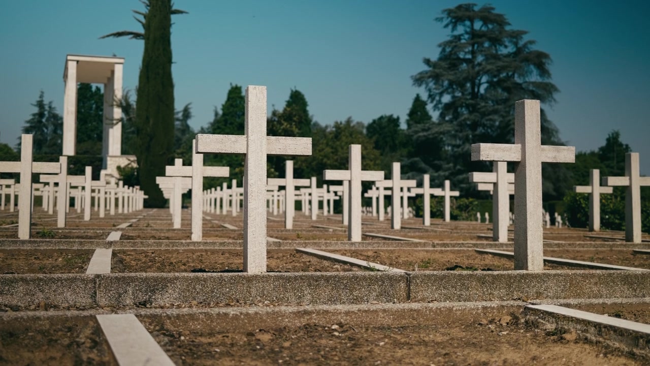 Croci tombali bianche in una tranquilla scena cimiteriale commemorativa.