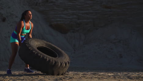 girl on sand quarry pushing wheel in training crossfit workout