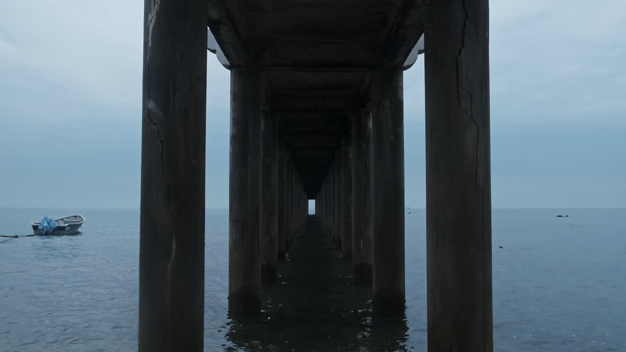 лодка, плывущая по океану в пасмурный день, с пирсом на переднем плане