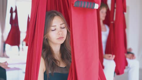 concentrated-woman-relaxes-in-red-hammock-after-fly-yoga