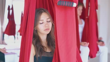 concentrated woman relaxes in red hammock after fly yoga