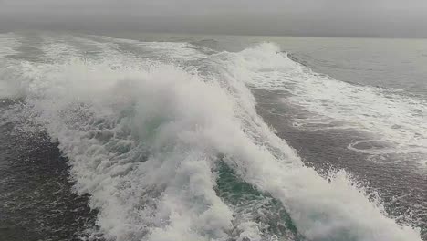 estela de agua vista desde atrás de un bote de motor en movimiento rápido en un día de cielo despejado, mar azul, superficie de agua