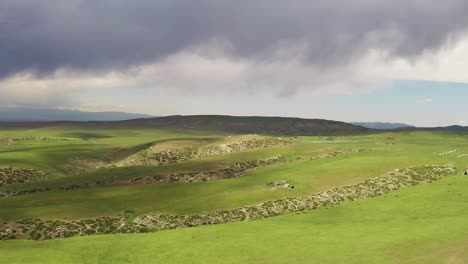 mountain peaks and grassland are under white clouds.