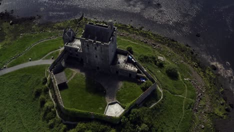 dynamic aerial shot reveals dunguaire castle from a top-down view to the busy coast road in kinvara